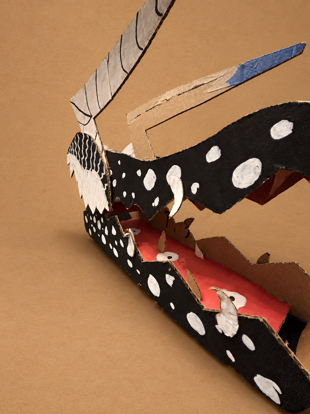 Dark Matter, a finished black, white, and red handcrafted cardboard dragon head